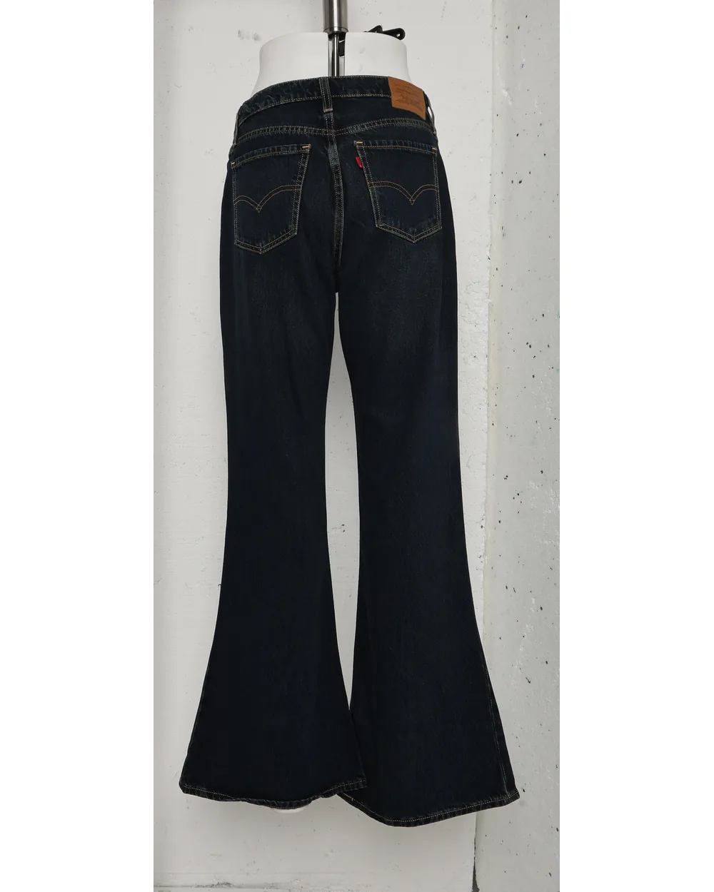Wide-leg denim as shot hanging against a bare concrete wall