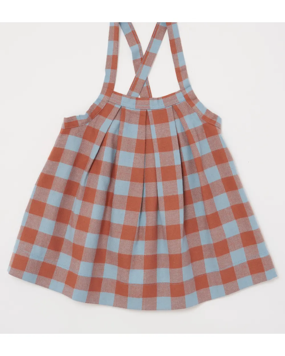Checked pinafore dress as shot on a studio backdrop